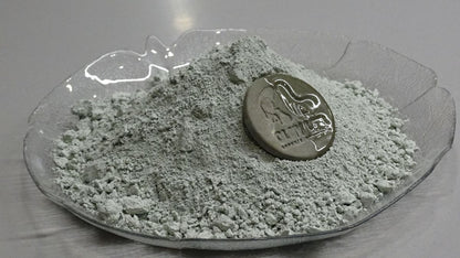 side view of green clay powder with a coin on top 