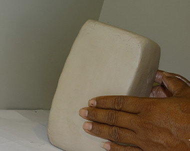 hand holding white stoneware clay block