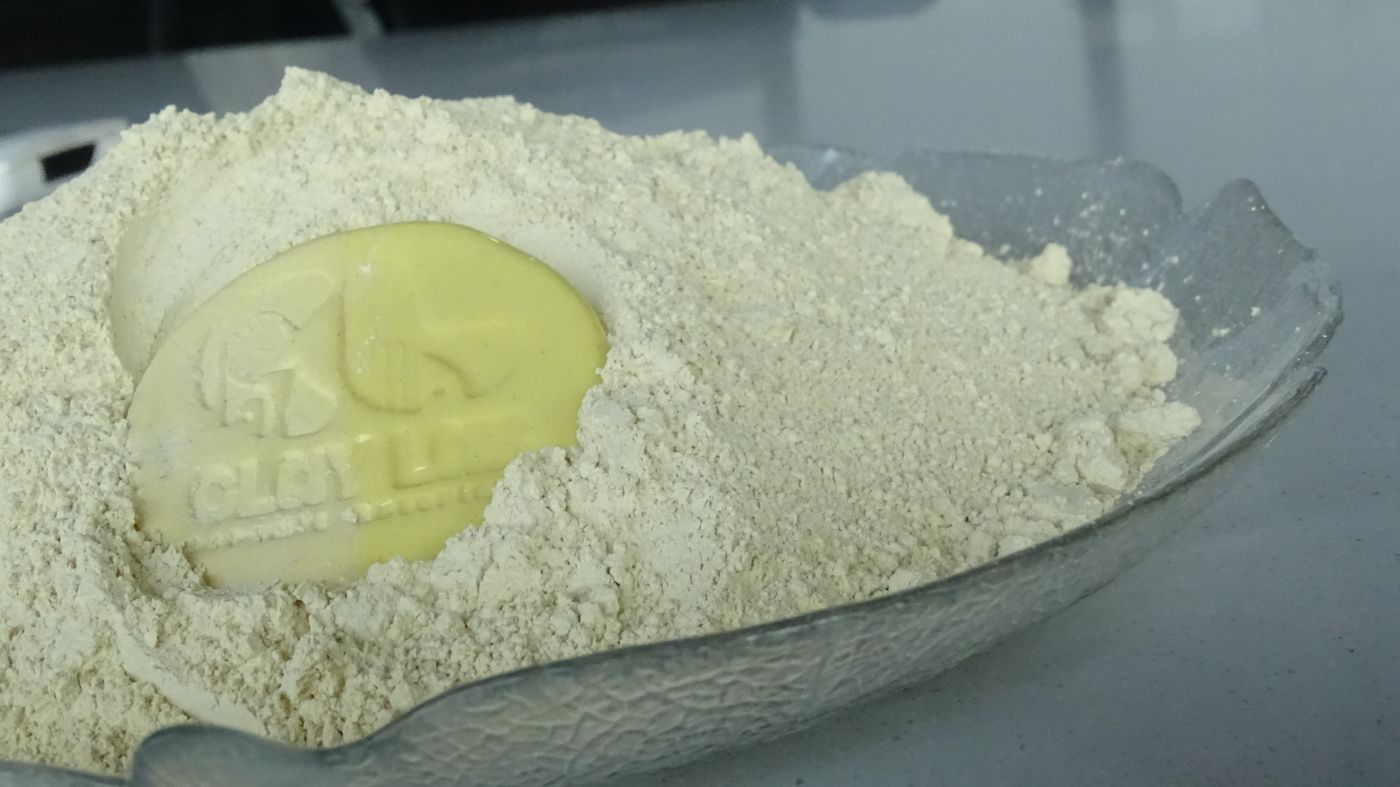 Yellow colored clay in a plate with a zoomed in view and a coin for its actual color