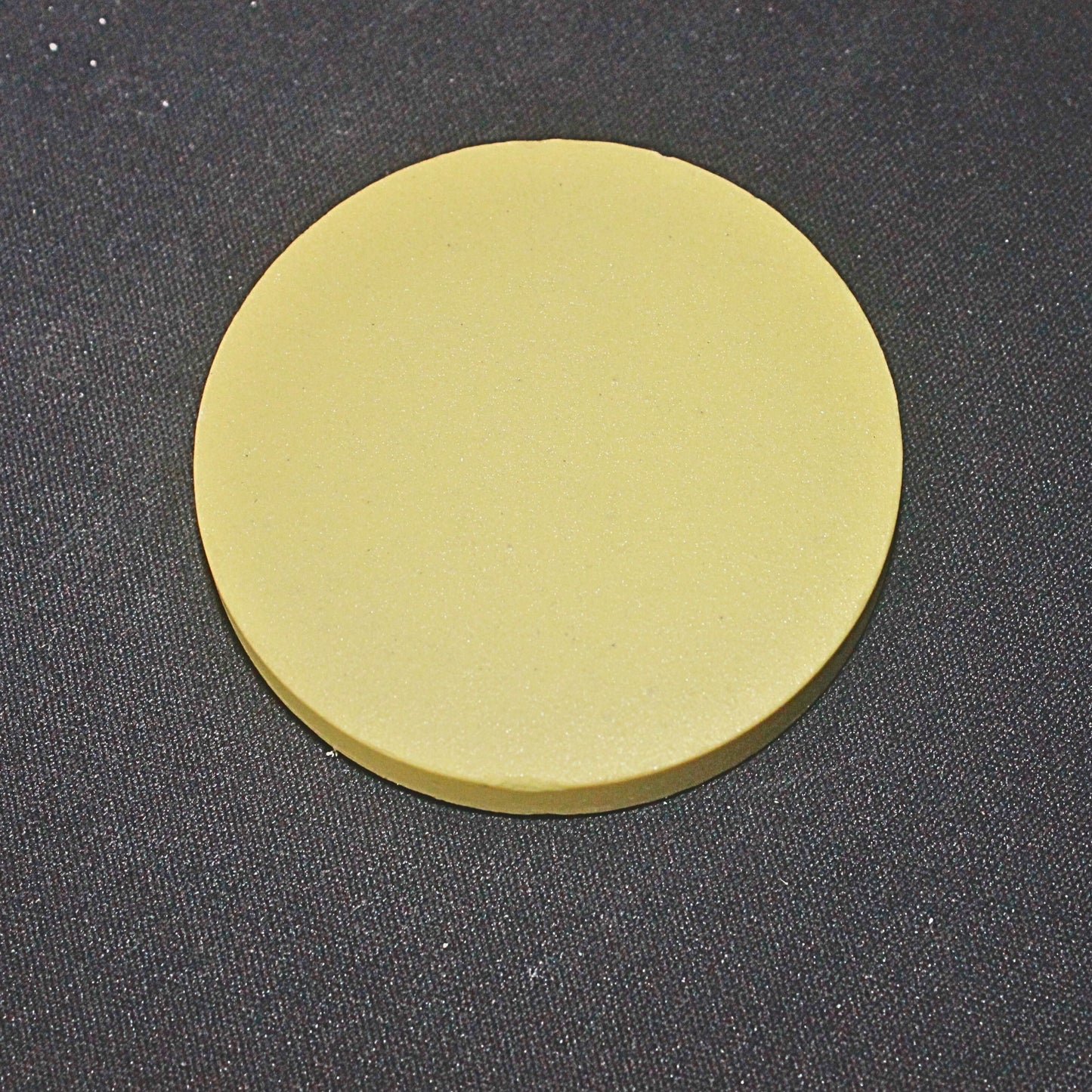 A yellow colored disc of stoneware color body